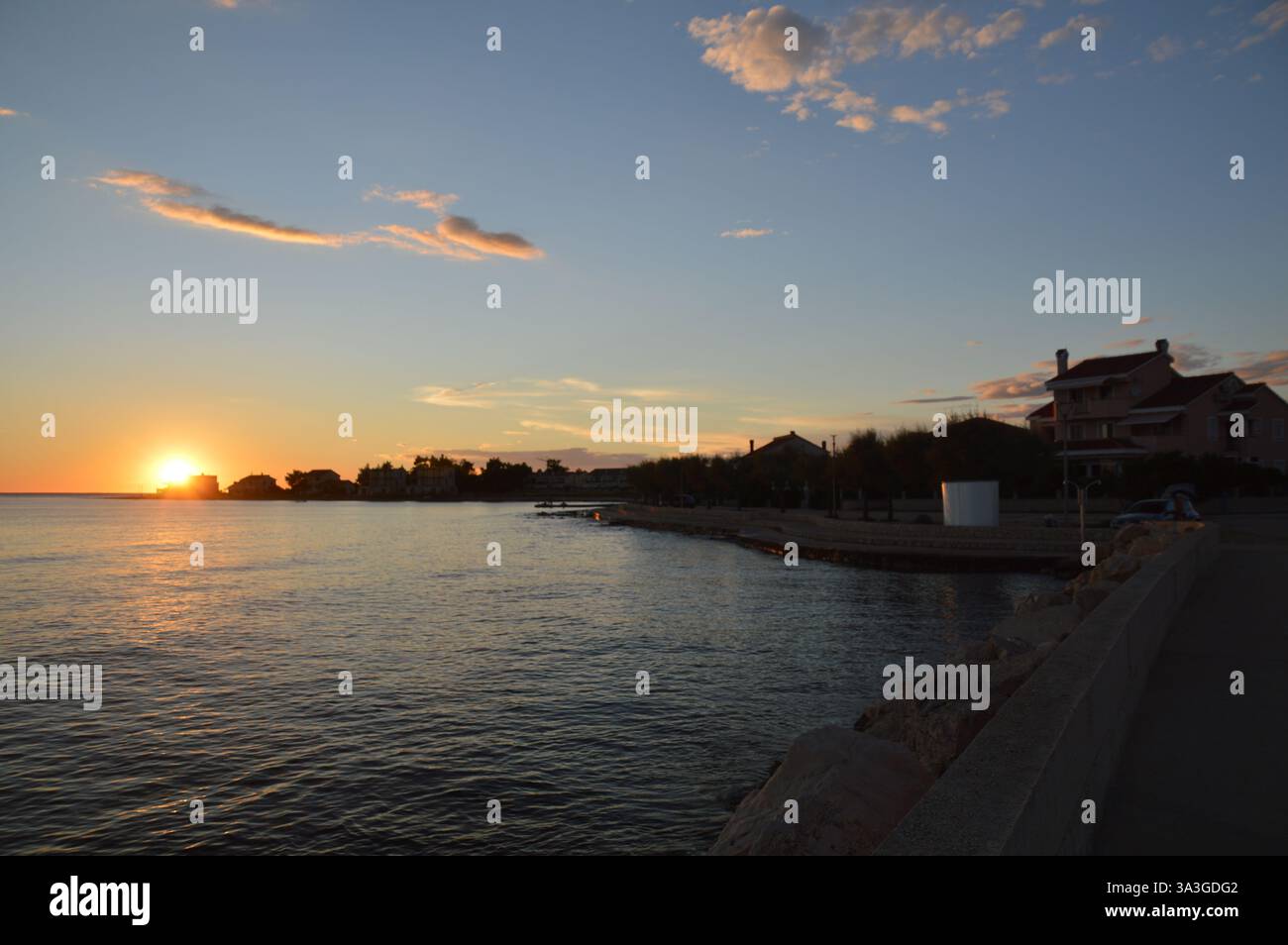 Atemberaubender Sonnenuntergang über Privlaka, Kroatien, mit leuchtenden Farbtönen, die sich auf die ruhige Adria spiegeln und eine ruhige Küstenlandschaft schaffen. Stockfoto