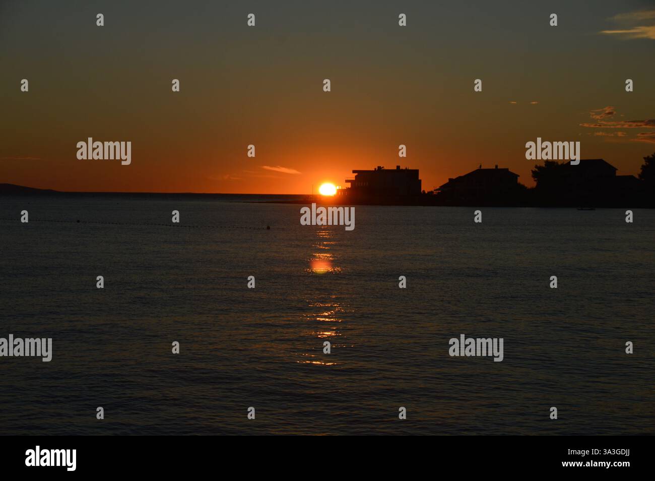 Atemberaubender Sonnenuntergang über Privlaka, Kroatien, mit leuchtenden Farbtönen, die sich auf die ruhige Adria spiegeln und eine ruhige Küstenlandschaft schaffen. Stockfoto