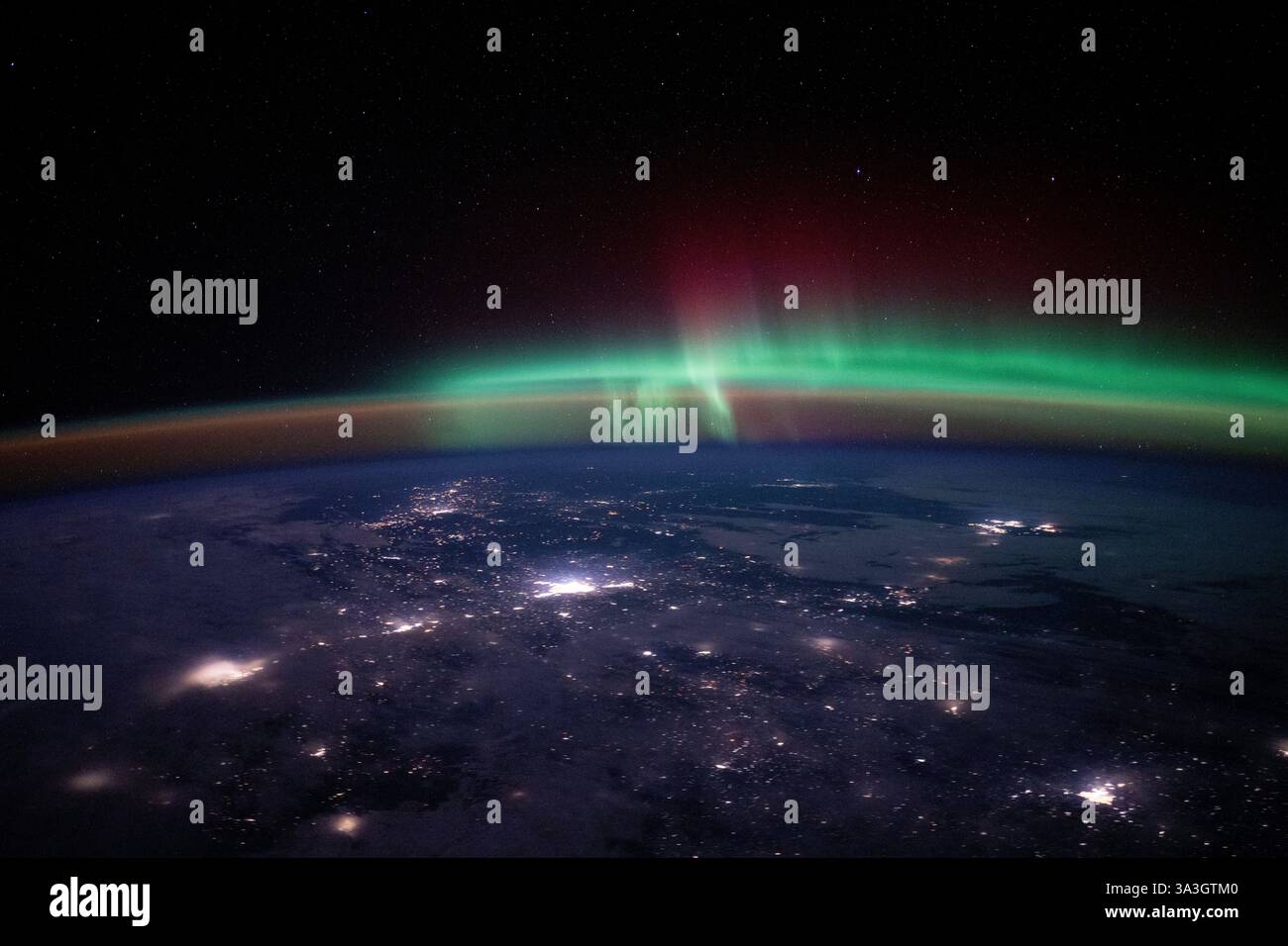 ISS - 05. März 2025 - Stadtlichter zeichnen die kanadische Landschaft unter einem atmosphärischen Leuchten und einer aurora borealis in diesem Foto aus dem I Stockfoto