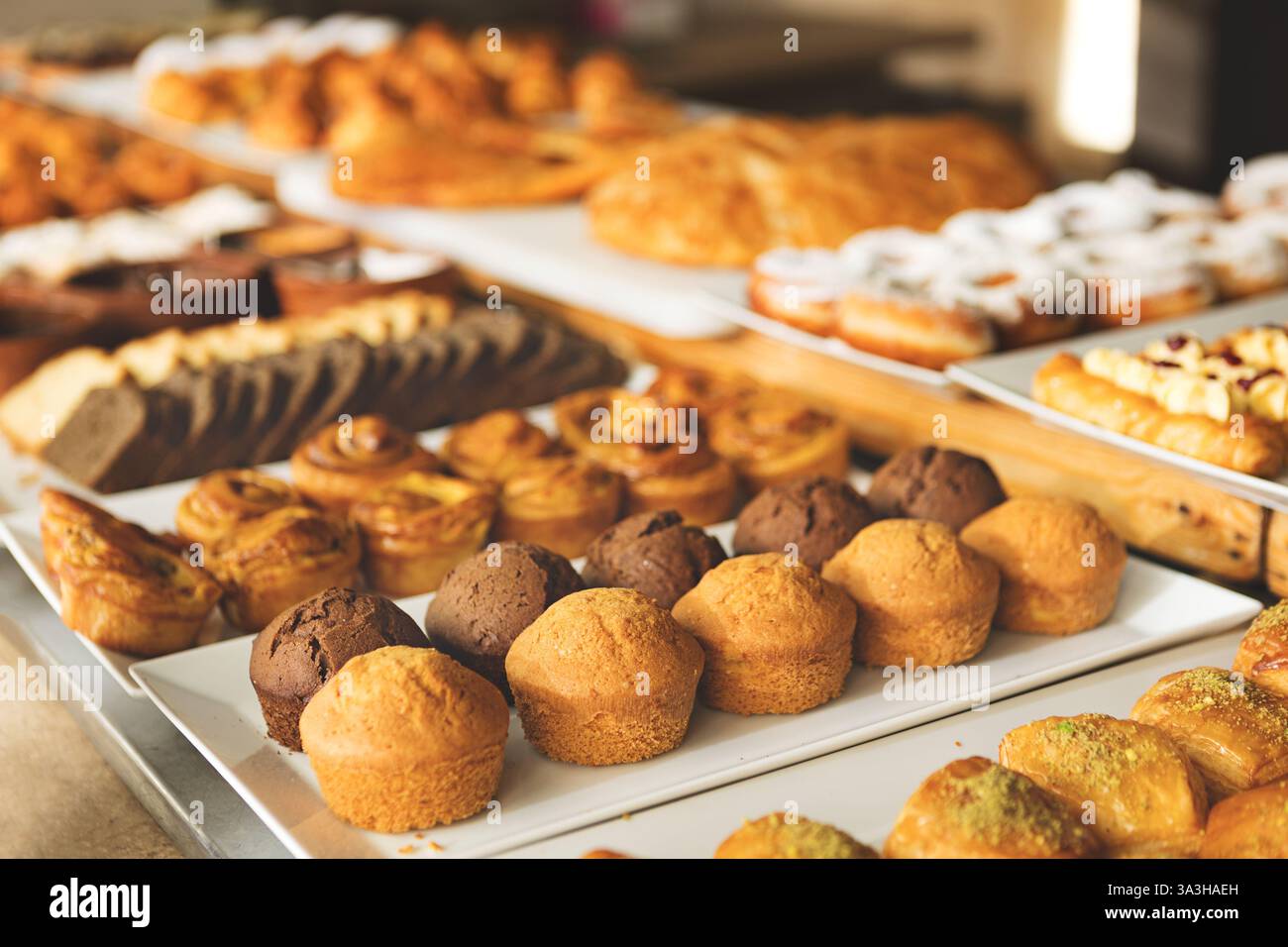 Eine große Auswahl an frisch gebackenem Gebäck, Muffins und süßen Brötchen wird auf dem Buffettisch in einer gemütlichen Bäckerei oder einem Café serviert, wo Frühstück, Brunch und ein Frühstück serviert werden Stockfoto