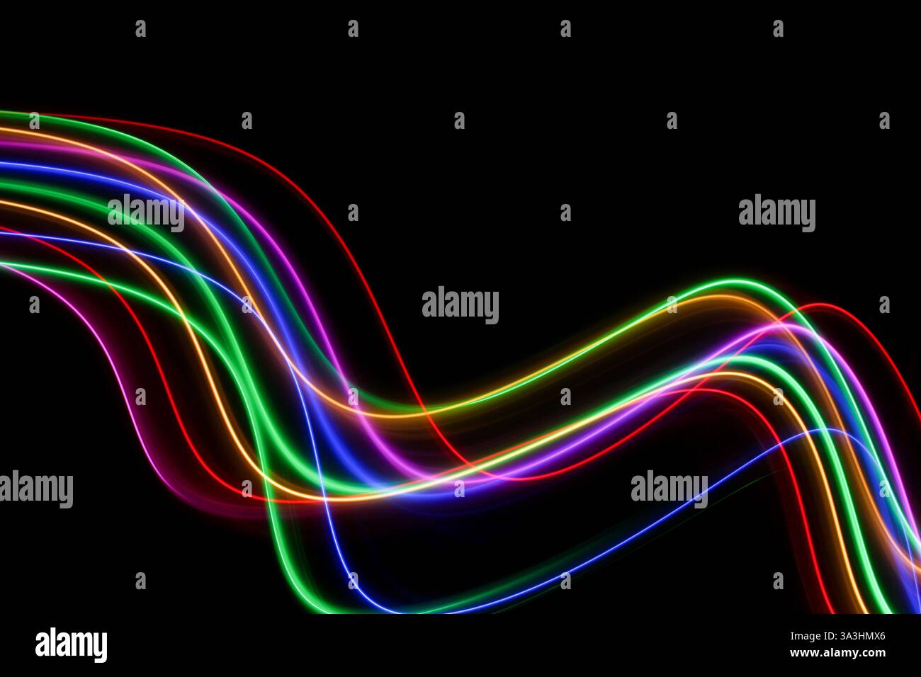 Ein Langzeitfoto von bunten Lichtern in wirbelnden Bewegungsmustern vor schwarzem Hintergrund Stockfoto