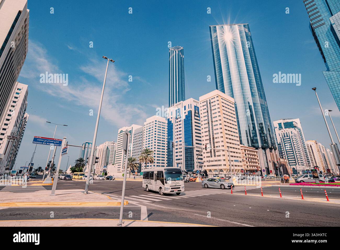 16. Januar 2025, Abu Dhabi, VAE: Minibusse und Autos fahren auf einer belebten Straße, moderne Wolkenkratzer im Hintergrund Stockfoto