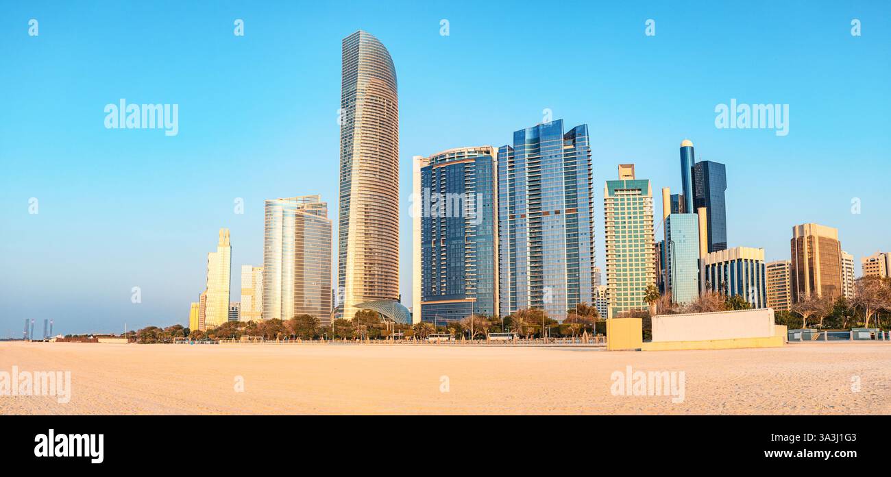 Panoramablick auf moderne Wolkenkratzer, die über dem Sandstrand Corniche in Abu Dhabi, VAE, aufragen und die städtische und natürliche Schönheit hervorheben Stockfoto
