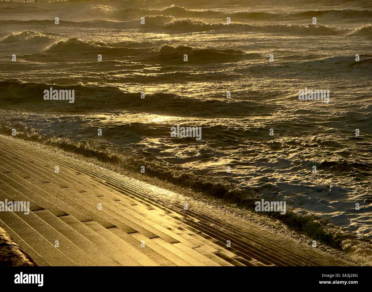 Wellen bei Flut gegen die Meeresmauer von Blackpool, beleuchtet durch Abendlicht - Smartphone-aufgenommenes Stockfoto
