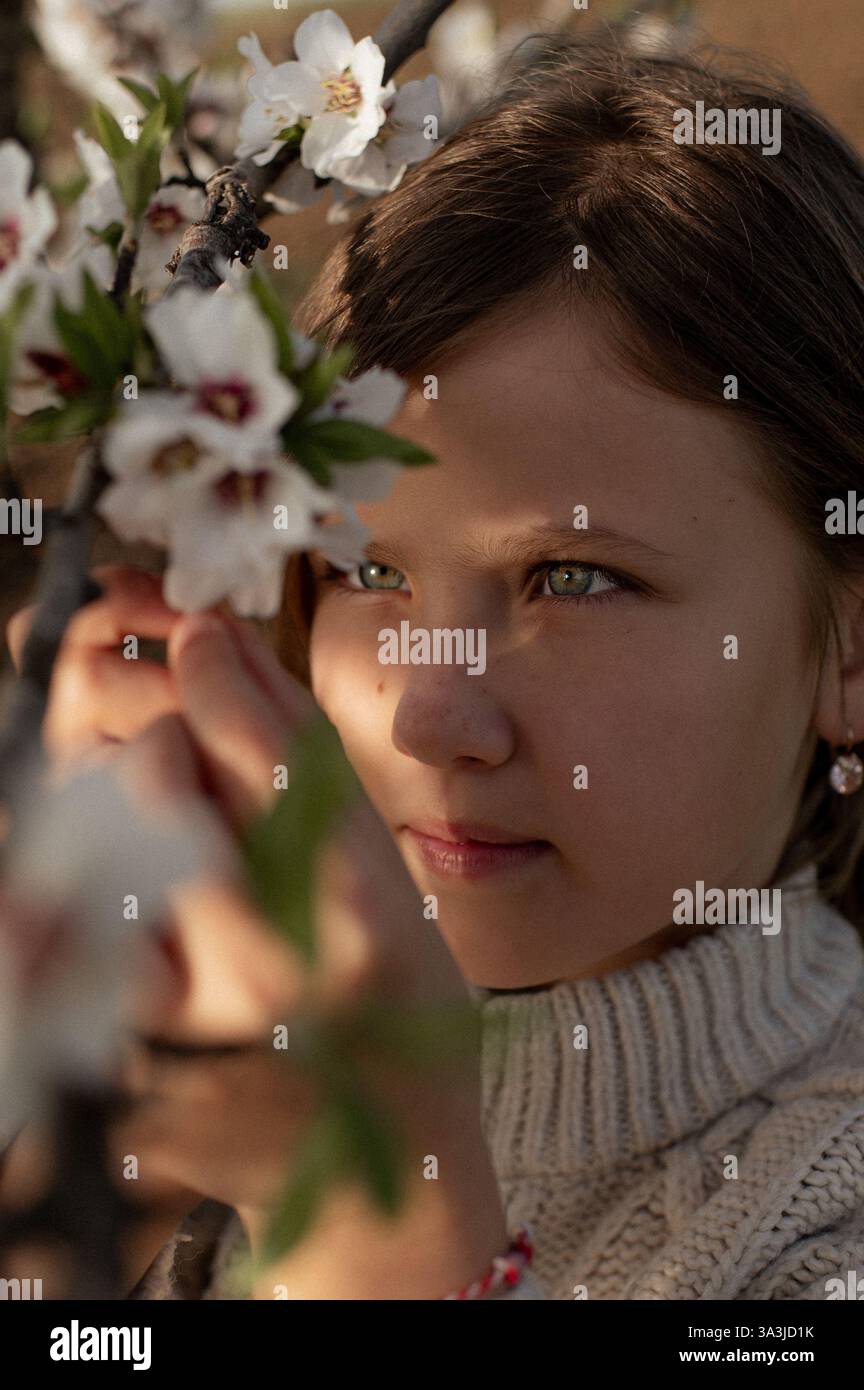 Ein fröhliches Mädchen spielt zwischen blühenden Mandelbäumen, ihr Lachen erfüllt die Frühlingsluft. Stockfoto
