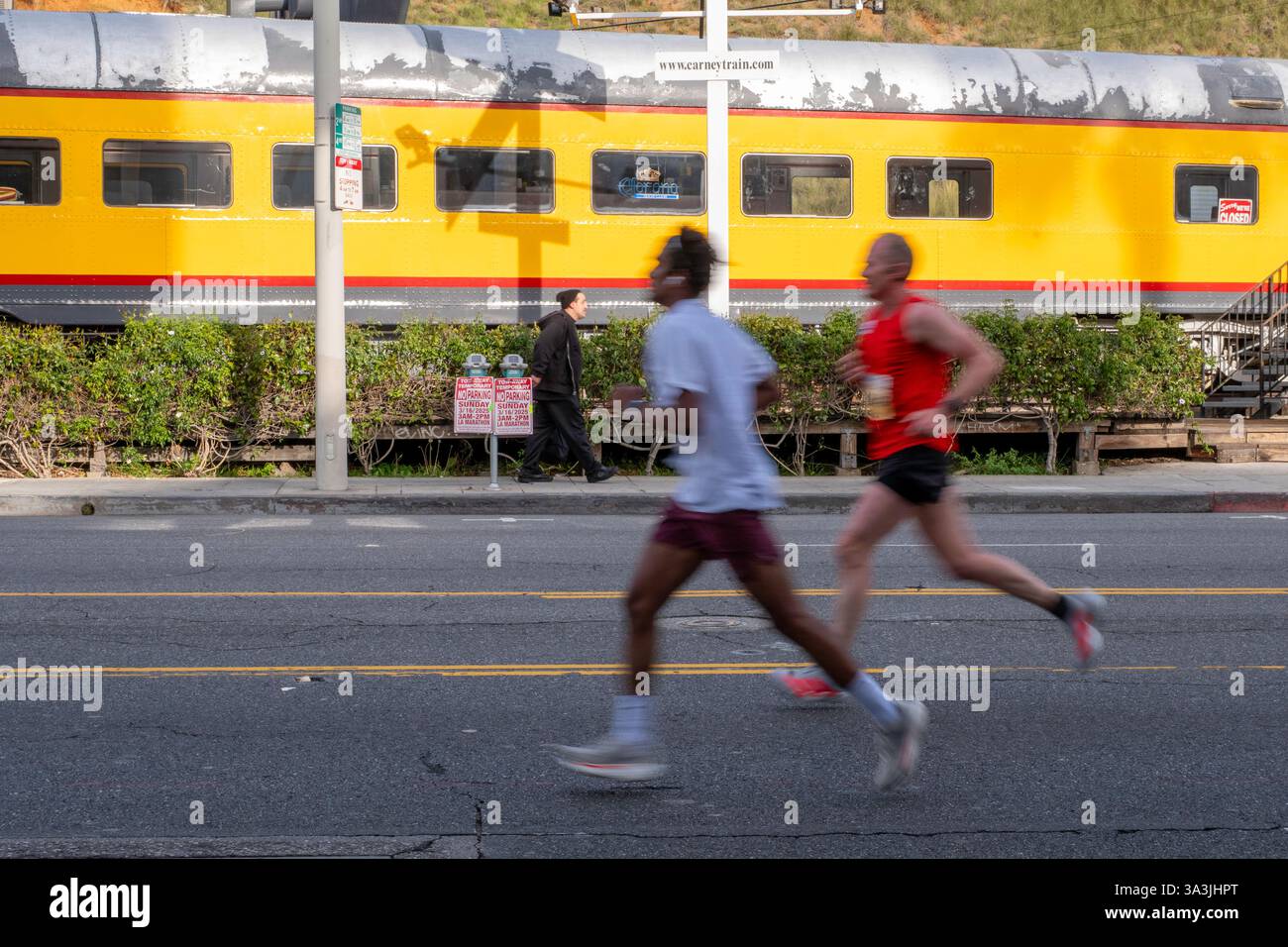 Los Angeles, USA. März 2025. Zwei Läufer passieren das berühmte Carney's Restaurant am Sunset Blvd. Beim 2025 Los Angeles Marathon/Mile 14. Quelle: Todd Felderstein/Alamy Live News Stockfoto