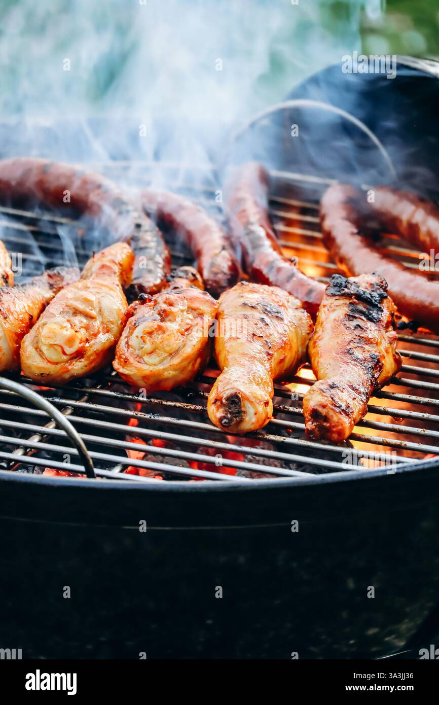 Hähnchenschenkel und Merguez-Würstchen, die auf einem Grill im Garten zubereitet werden Stockfoto