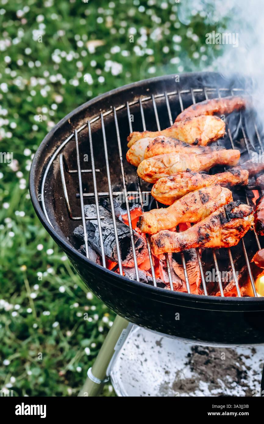 Hähnchenschenkel und Merguez-Würstchen, die auf einem Grill im Garten zubereitet werden Stockfoto