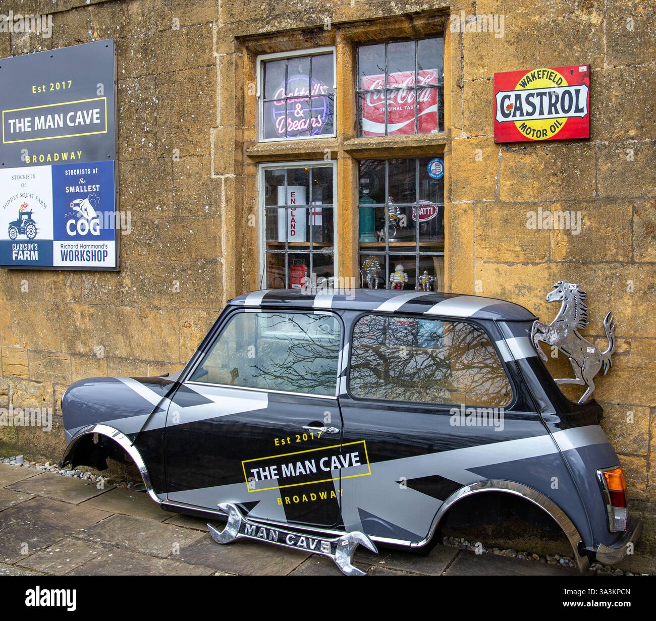 Klassischer Mini Cooper Half Car an der Wand der man Cave mit Vintage-Schildern und Backsteinfassungen im Broadway, Großbritannien Stockfoto