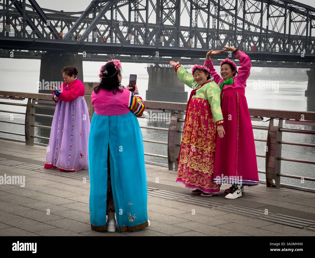 Touristen posieren für Bilder in traditionellen koreanischen Outfits entlang des Flusses Yalu, der die Grenze zwischen Nordkorea und China abgrenzt. Dand Stockfoto