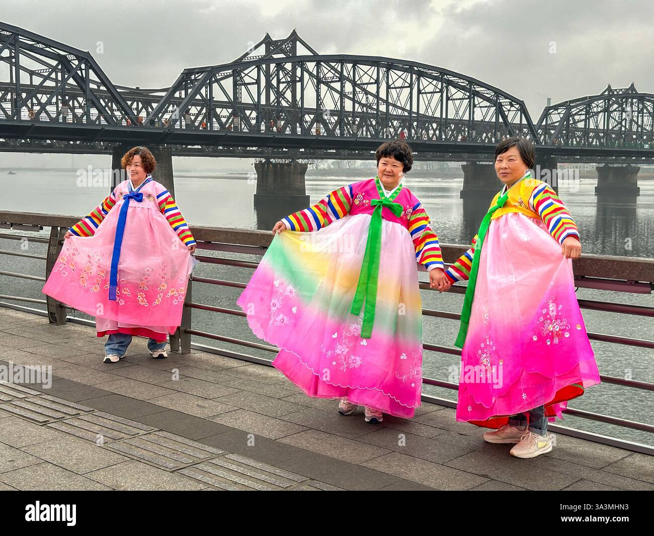 Touristen posieren für Bilder in traditionellen koreanischen Outfits entlang des Flusses Yalu, der die Grenze zwischen Nordkorea und China abgrenzt. Dand Stockfoto