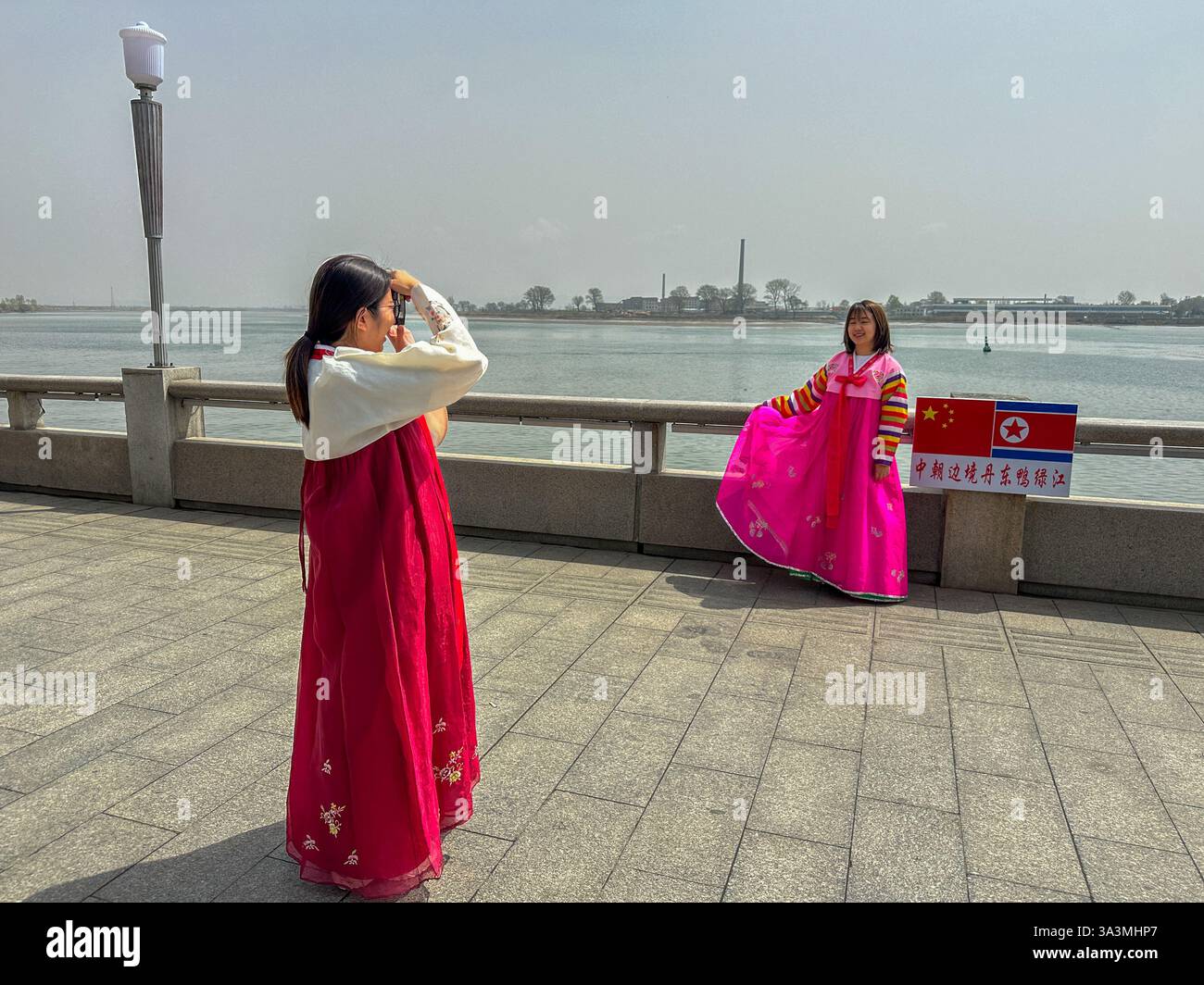 Touristen posieren für Bilder in traditionellen koreanischen Outfits entlang des Flusses Yalu, der die Grenze zwischen Nordkorea und China abgrenzt. Dand Stockfoto