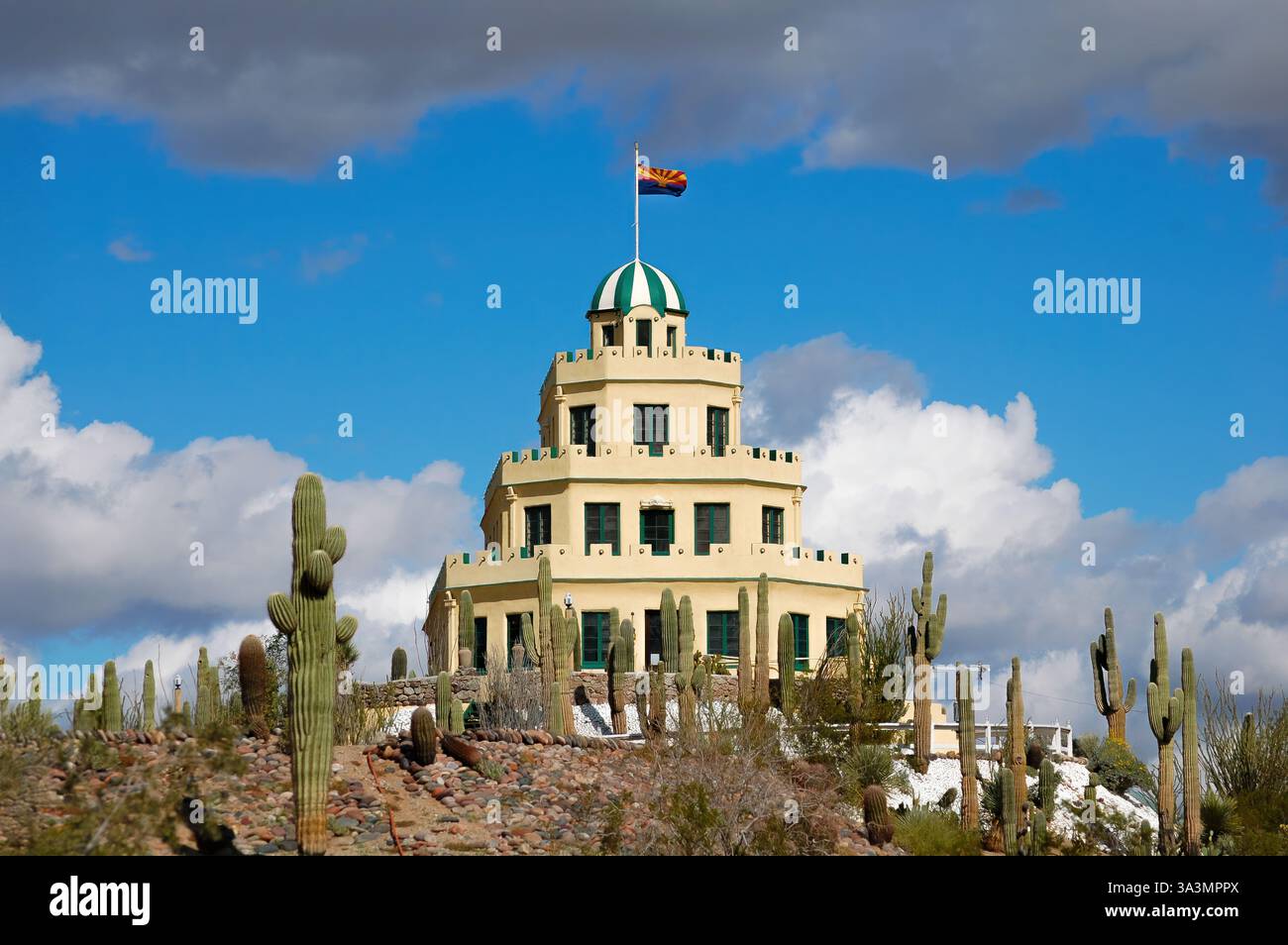 Tovrea Castle in Phoenix, Arizona, bekannt als „Wedding Cake Castle“, umgeben von Saguaro-Kakteen unter hellem Wüstentag. Stockfoto