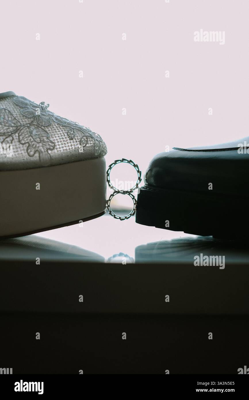 Eine symbolische Darstellung einer Hochzeit. Nahaufnahme mit den Schuhen der Braut, den Schuhen des Bräutigams und den Eheringen, die ihre vereinigung symbolisieren. T Stockfoto