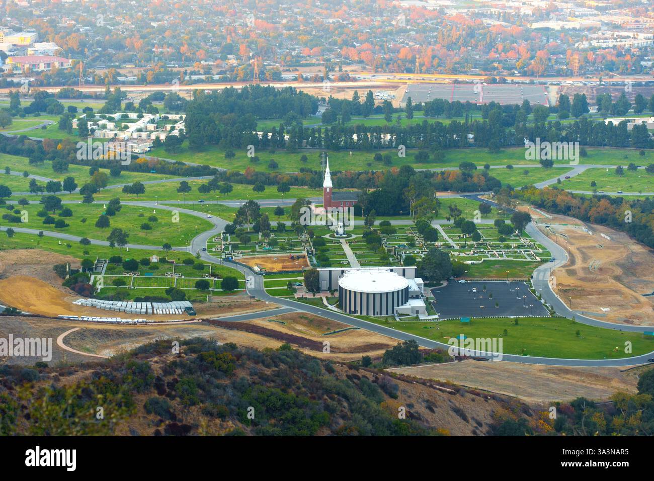 Aus der Vogelperspektive des Forest Lawn Memorial Park mit weitläufigen Grundstücken und Baumaterialstapeln, die die laufenden Verbesserungen in Los hervorheben Stockfoto