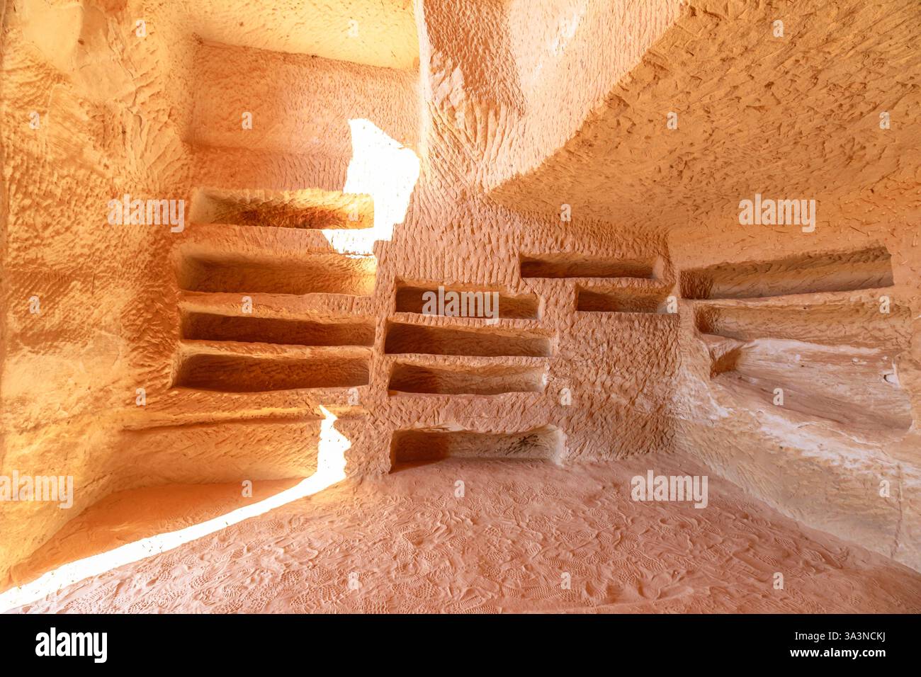 Das Sonnenlicht, das das Innere eines in Felsen gehauenen Grabes Jabal Al-Banat in Hegra, Al-Ula, Saudi-Arabien, beleuchtet, offenbart komplizierte Details und alte Begräbnisse Stockfoto