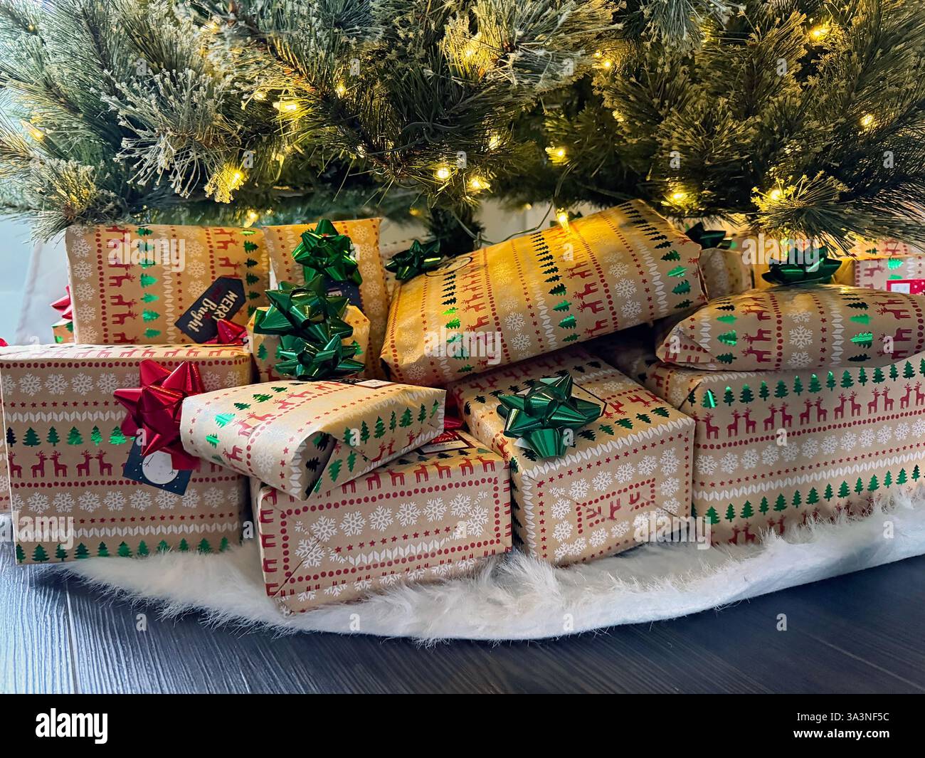 Weihnachtsgeschenke in festliches Papier unter einem beleuchteten Baum Stockfoto