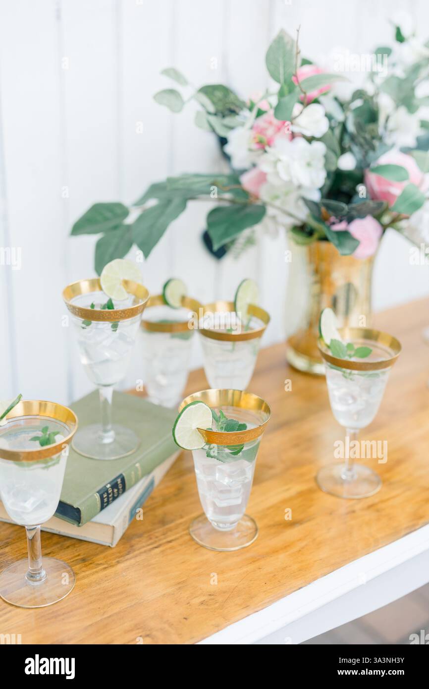 Erfrischende Limettencocktails in Gläsern mit goldenem Rand und Blumendekor Stockfoto