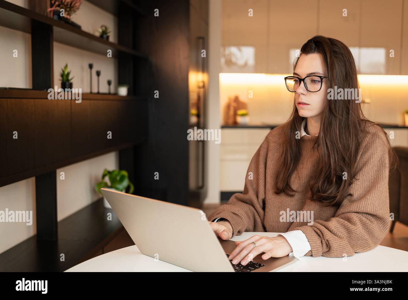 Frau mit Brille, die im Wohnzimmer am Laptop arbeitet Stockfoto