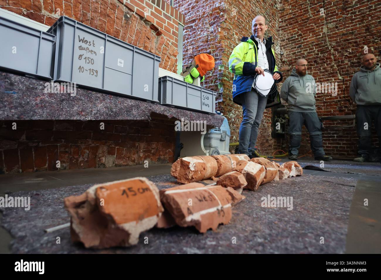 Hamburg, Deutschland. März 2025. Uwe Pfeiffer (l), Projektmanager, steht bei einer Presseveranstaltung hinter einem Bohrkern im Turm von St. Michael. Der Turm der Hamburger Hauptkirche St. Michael weist tiefe Risse auf und die Renovierungsarbeiten sollen im Sommer beginnen. Quelle: Christian Charisius/dpa/Alamy Live News Stockfoto