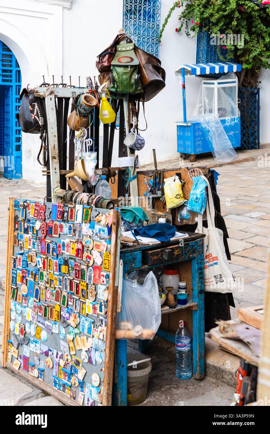Ein kleiner Verkaufsstand auf der Straße, an dem Kühlschrankmagnete, Ledergürtel und Souvenirs im UNESCO-Weltkulturerbe Sidi Bou Said, Tunis, verkauft werden Stockfoto