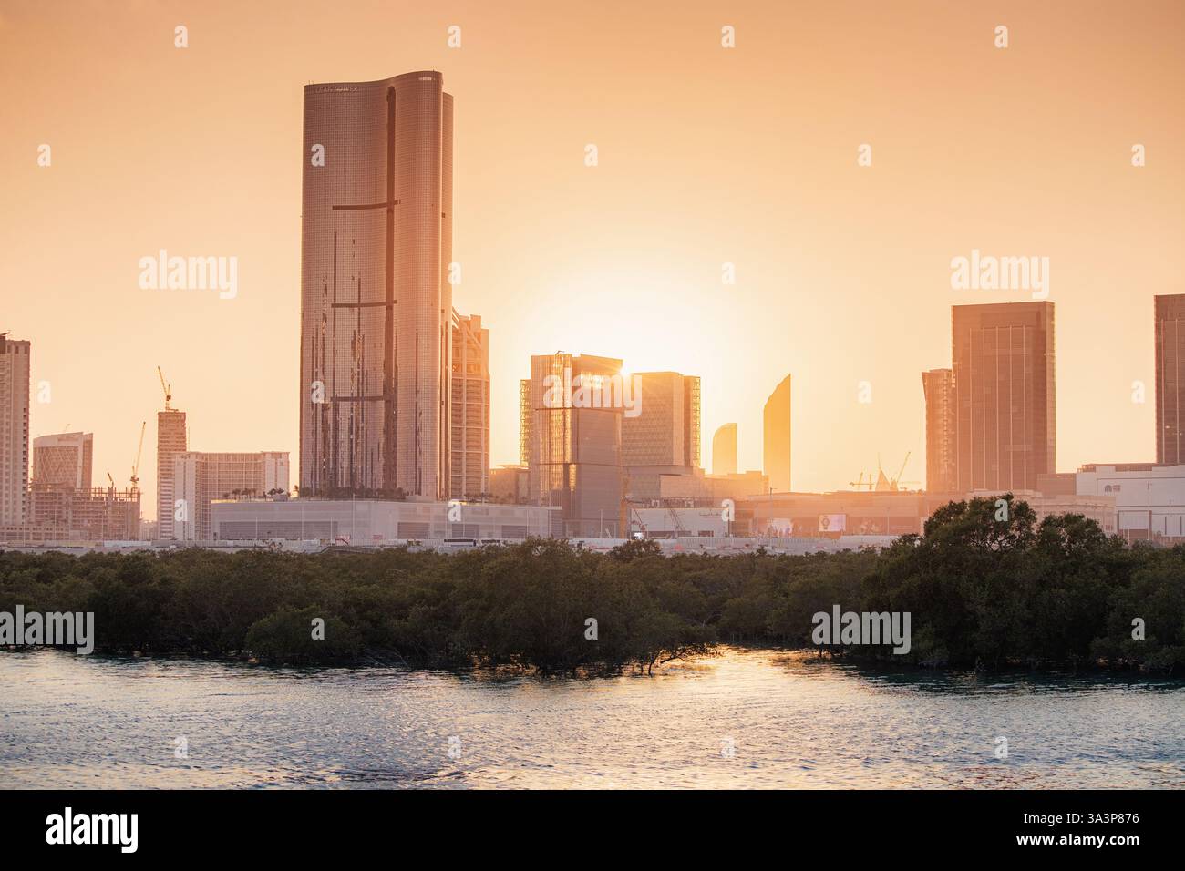 21. Januar 2025, Abu Dhabi, VAE: Panoramablick auf die Skyline von Abu Dhabi bei Sonnenuntergang mit Wolkenkratzern und Mangroven, die sich auf dem Wasser spiegeln Stockfoto