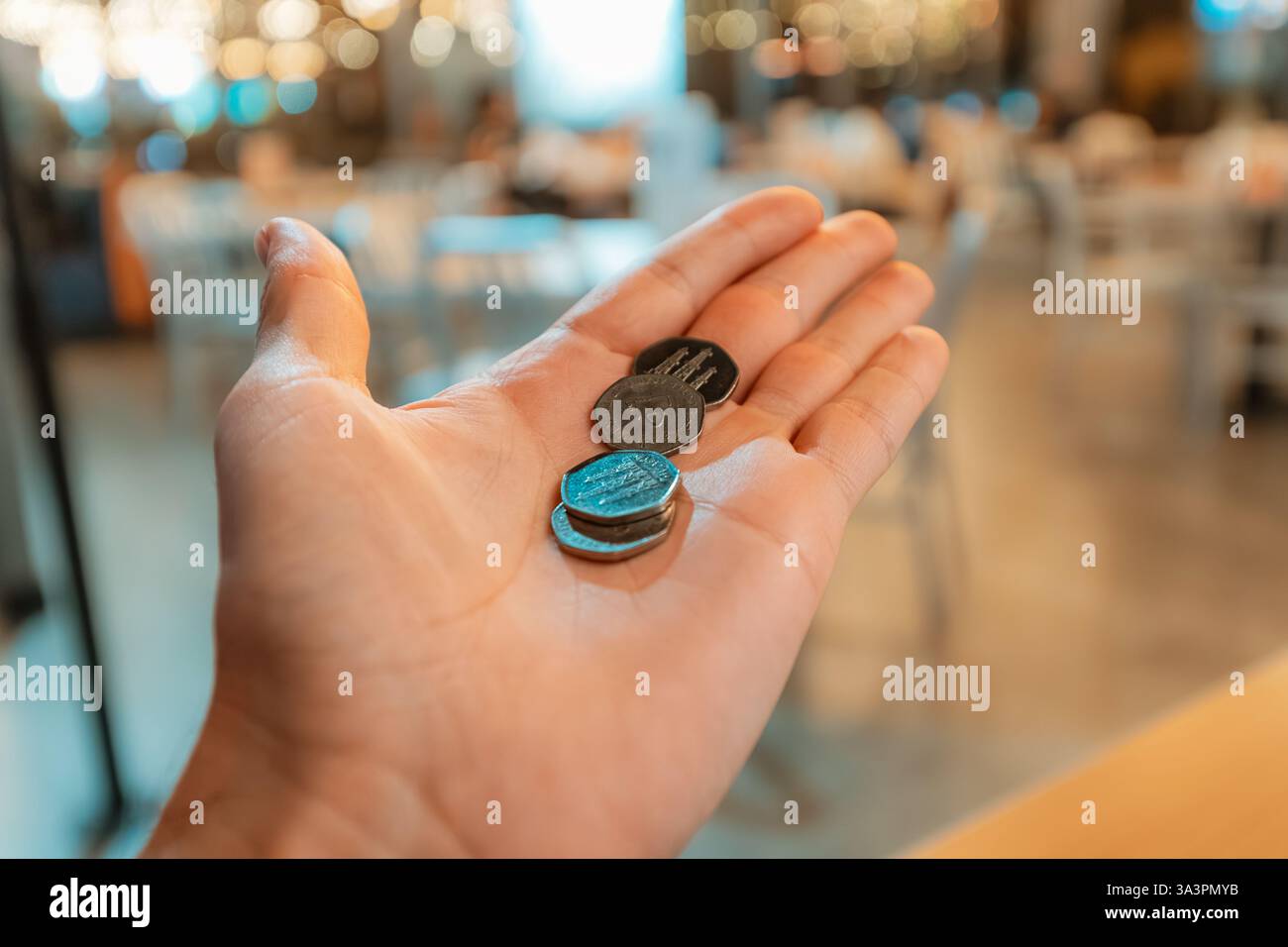Kunde hält AED-Dirham-Münzen in einem Restaurant, bereitet sich auf Zahlung oder Trinkgeld vor Stockfoto