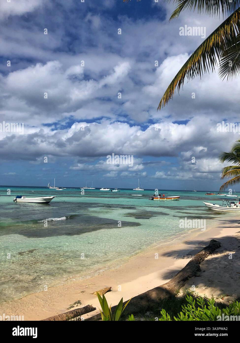 Eine malerische Szene von der Insel Saona, mit kleinen Booten auf ruhigem Wasser, mit atemberaubenden Wolken und der Schönheit der Küste - Smartphone-aufgenommenes Stockfoto