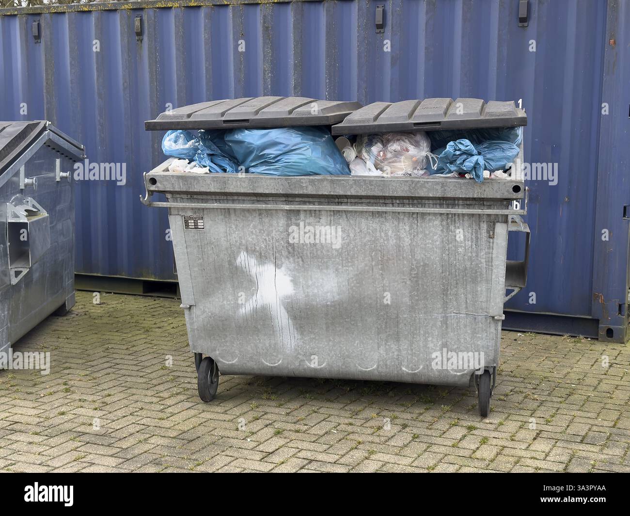 Voller Abfallbehälter nicht durch Müllsammlung geleert Abfallbehälter überfüllt mit Müllsäcken und blauen Kunststoffsäcken Müllsäcken, Deutschland, Europa Stockfoto