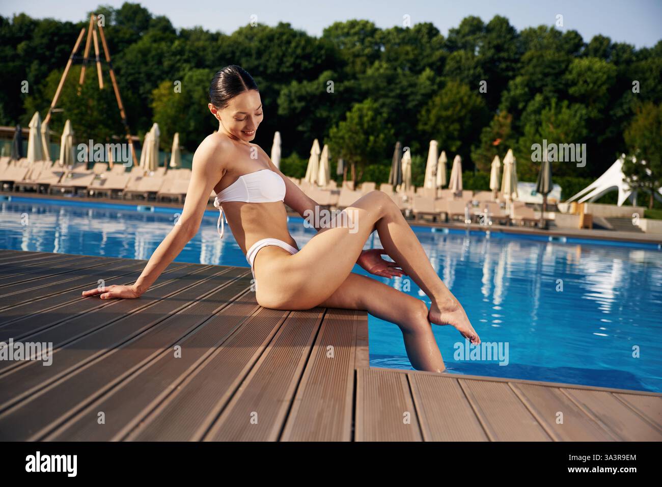 Die schöne Frau im Bikini ruht am Pool aus. Stockfoto