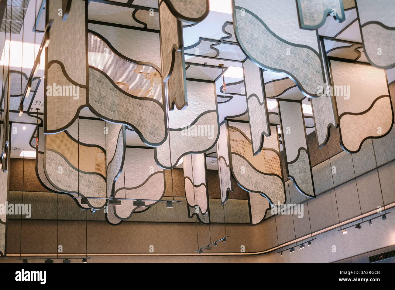 Eine moderne und künstlerische Deckendekoration mit strukturierten Paneelen, die an konturierten Metallrahmen hängen. Diese auffällige Installation kombiniert Geom Stockfoto