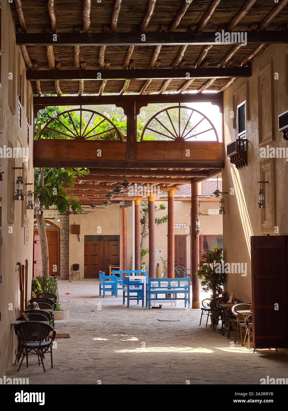Sonnendurchfluteter arabischer Innenhof mit Holzarchitektur in Khorfakkan, Vereinigte Arabische Emirate - Smartphone-aufgenommenes Stockfoto