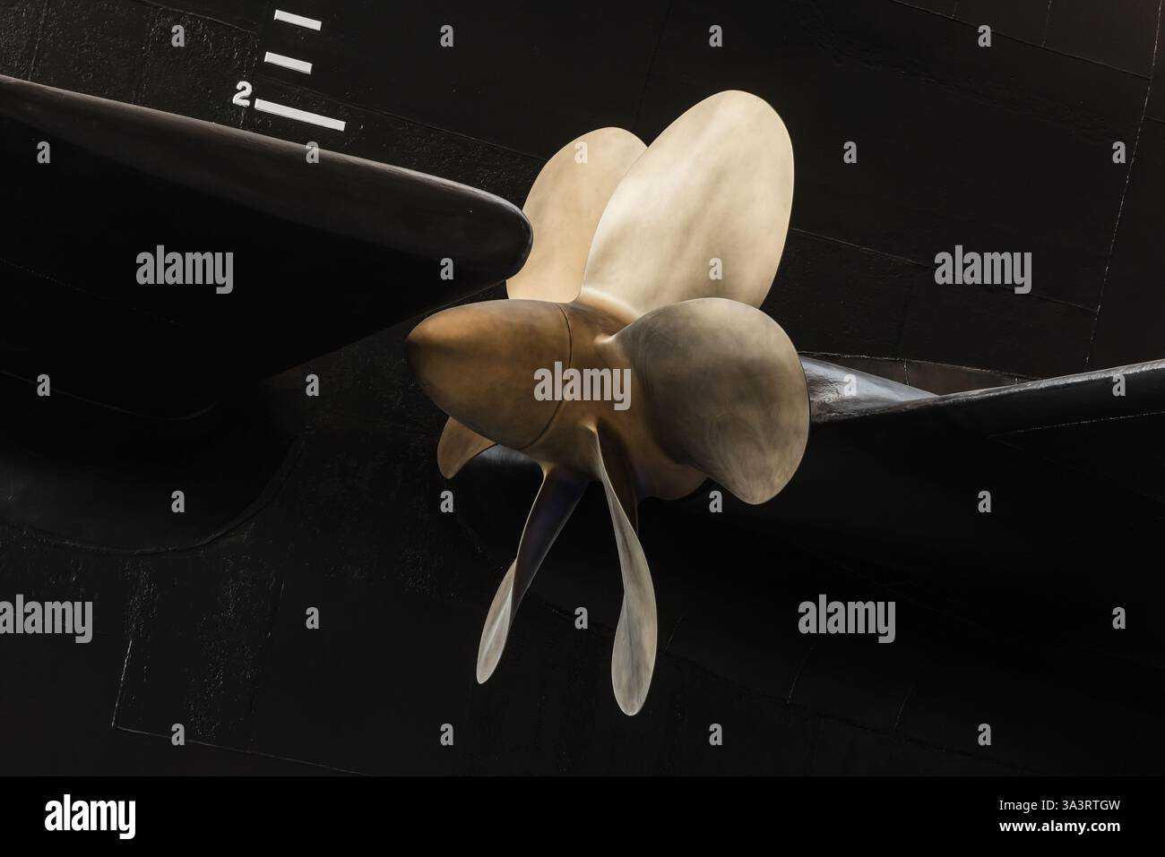 Detaillierte Ansicht eines metallischen U-Boot-Propellers, der an einem schwarzen Rumpf befestigt ist, zeigt das technische Design. Geeignet für maritime und industrielle Anwendungen Stockfoto