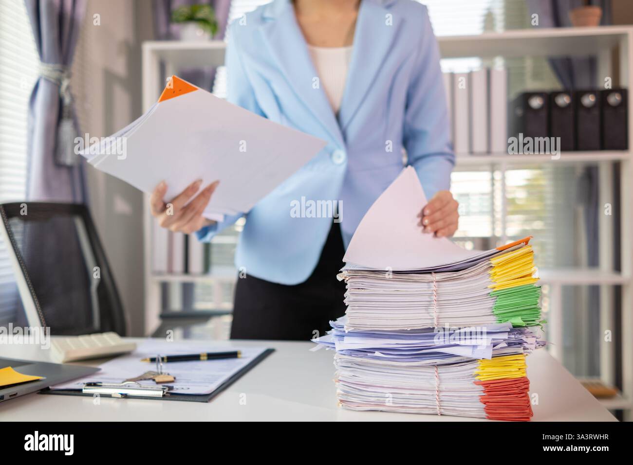 Geschäftsmann, der wichtige Vertragsdokumente aus einem Stapel von Dokumenten auf dem Tisch sucht, bestätigt die Vereinbarung, die sie mit einem Investor unterzeichnet hat. Geschäftsmann-Scheck Stockfoto