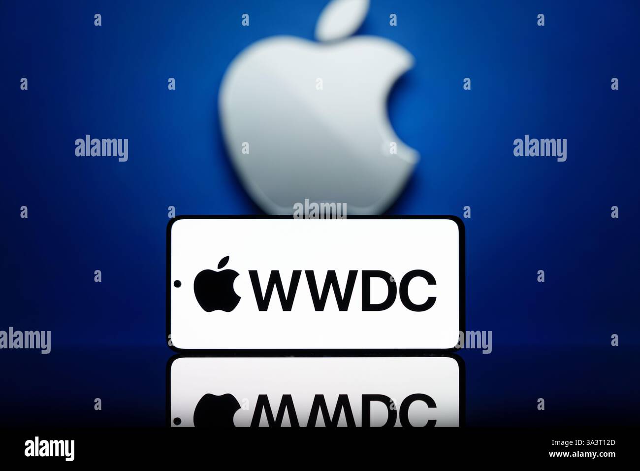Smartphone mit WWDC-Logo und unscharfem Apple-Logo im Hintergrund. Apple Entwicklerkonferenz und Technologie-Event-Konzept Stockfoto