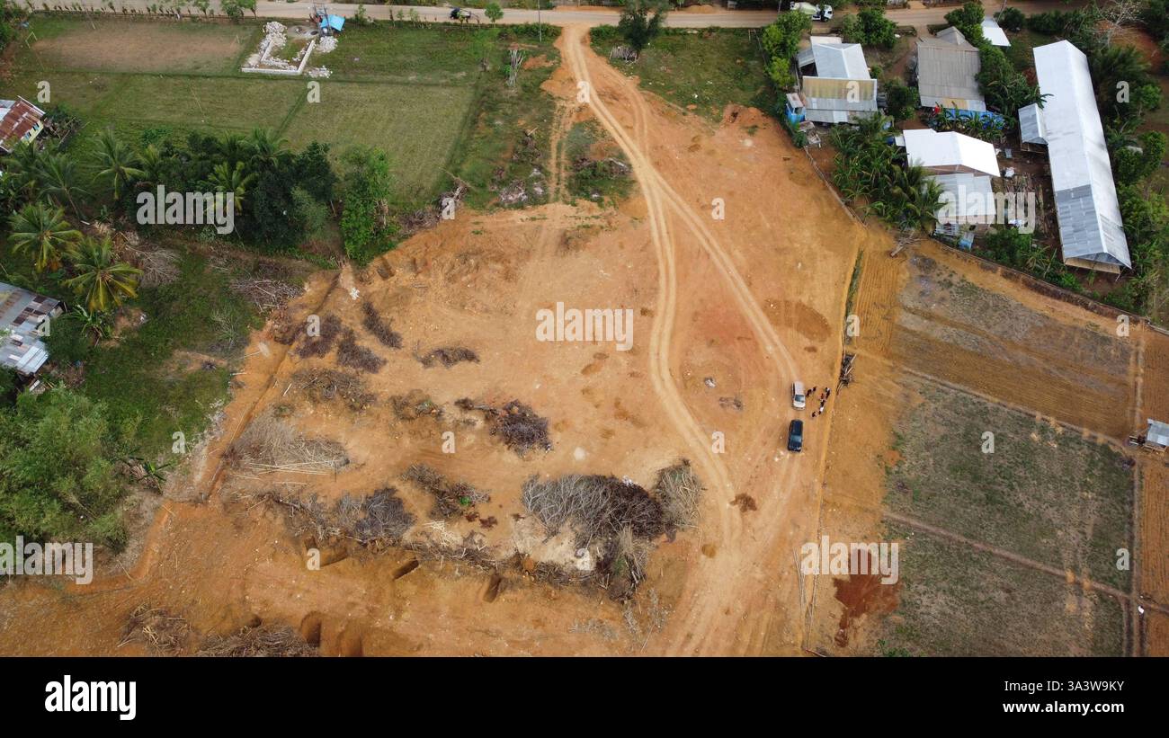 Eine hochauflösende Luftaufnahme einer Landrodung in einem ländlichen Gebiet, die Baumaschinen, unbefestigte Straßen und umliegende Grünflächen zeigt. Ideal für Stockfoto