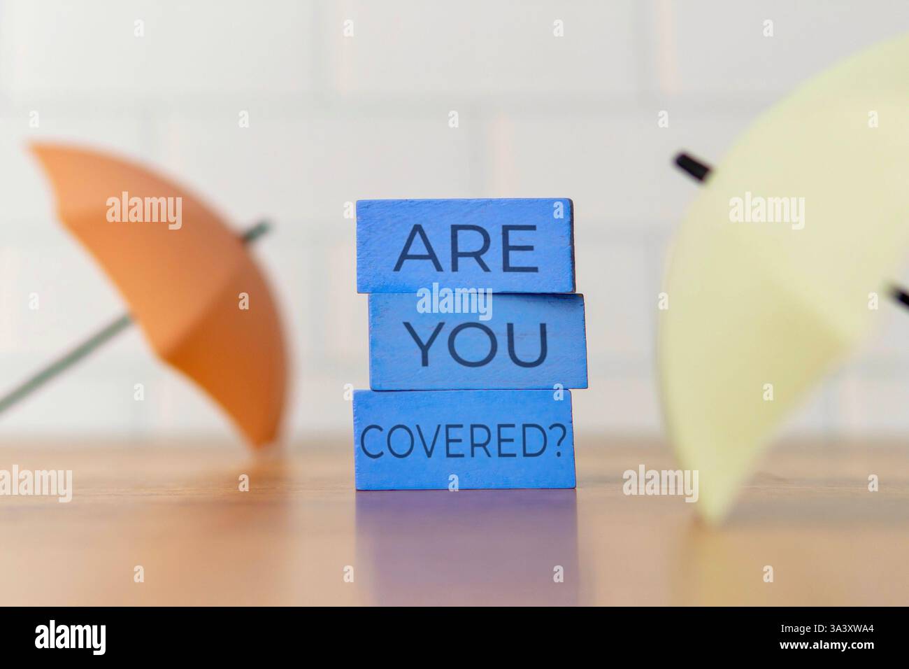 Ein kleiner Regenschirm mit den Worten „sind Sie bedeckt?“. Schutz, Versicherung, finanzielles Sicherheitskonzept. Stockfoto