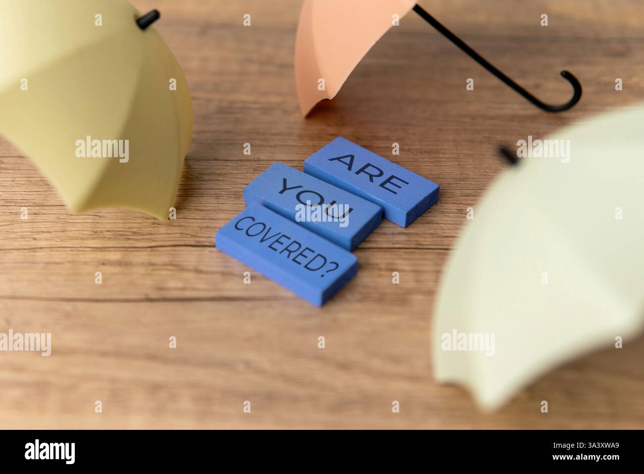 Ein kleiner Regenschirm mit den Worten „sind Sie bedeckt?“. Schutz, Versicherung, finanzielles Sicherheitskonzept. Stockfoto