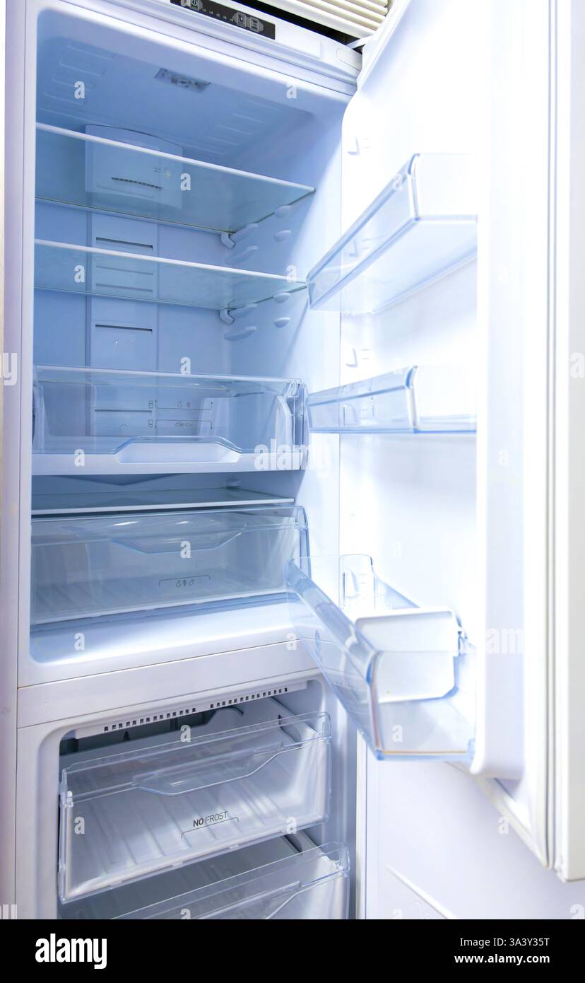 Ein Kühlschrank ist offen und das Innere ist leer. Die Tür ist weiß und die Regale sind frei Stockfoto