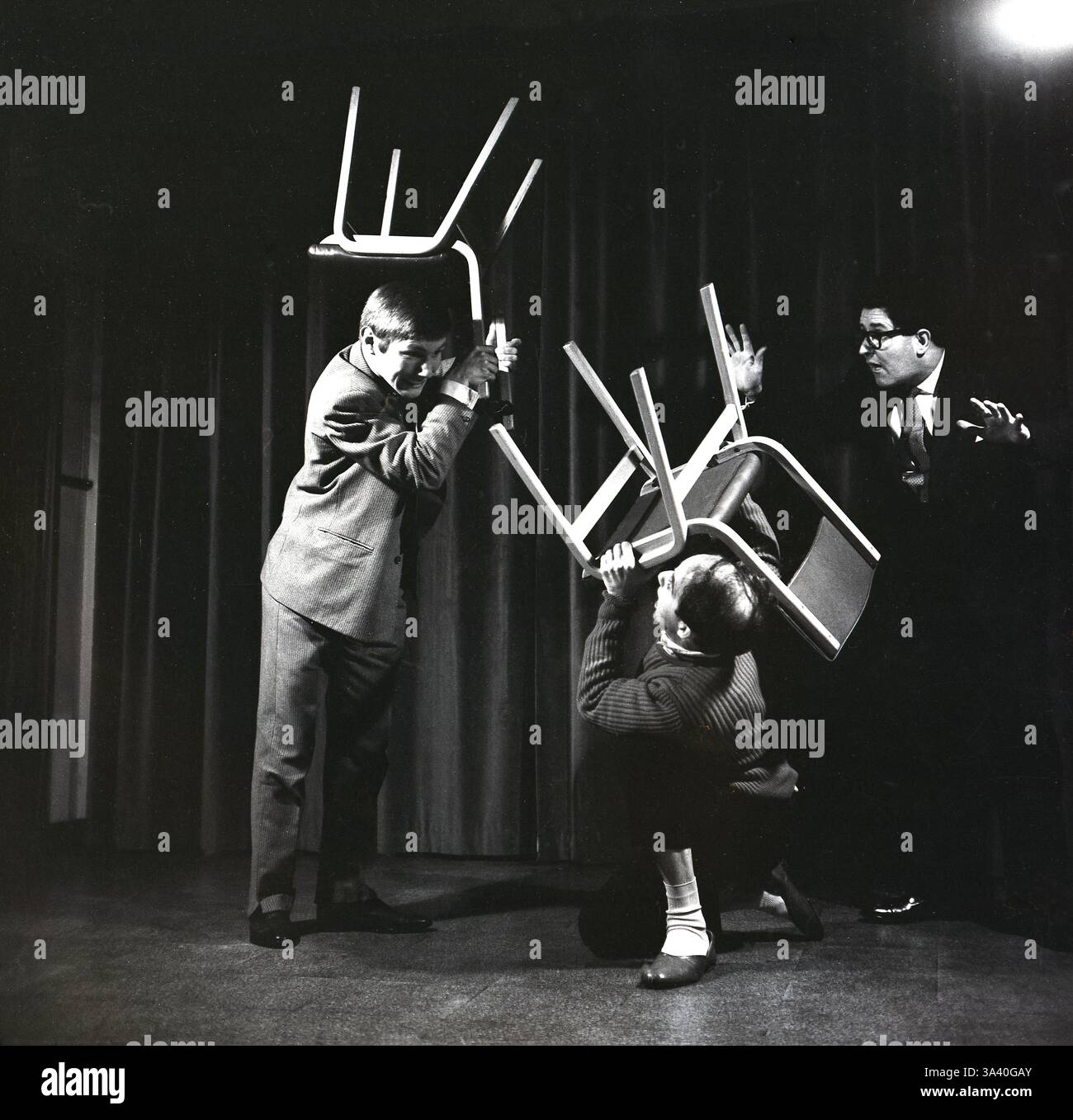 1965, historische Schauspieler in „The Birthday Party“ von Harold Pinter, seinem ersten abendfüllenden Stück und einem seiner bekanntesten und am häufigsten aufgenommenen Stücke. Im Mittelpunkt der Handlung steht eine kleine Geburtstagsfeier für Stanley Webber, einen einstigen Klavierspieler im Alter von 30 Jahren, der in einer heruntergekommenen Pension am Meer lebt. Die Pension wird von Meg und Petey Boles geleitet, die die Party für ihn abhalten. Zwei unheimliche Fremde, Goldberg und McCann, kommen und scheinen nach ihm zu suchen. Unter ihnen verwandeln sie Stanleys scheinbar harmlose Geburtstagsparty in einen Albtraum. Stockfoto