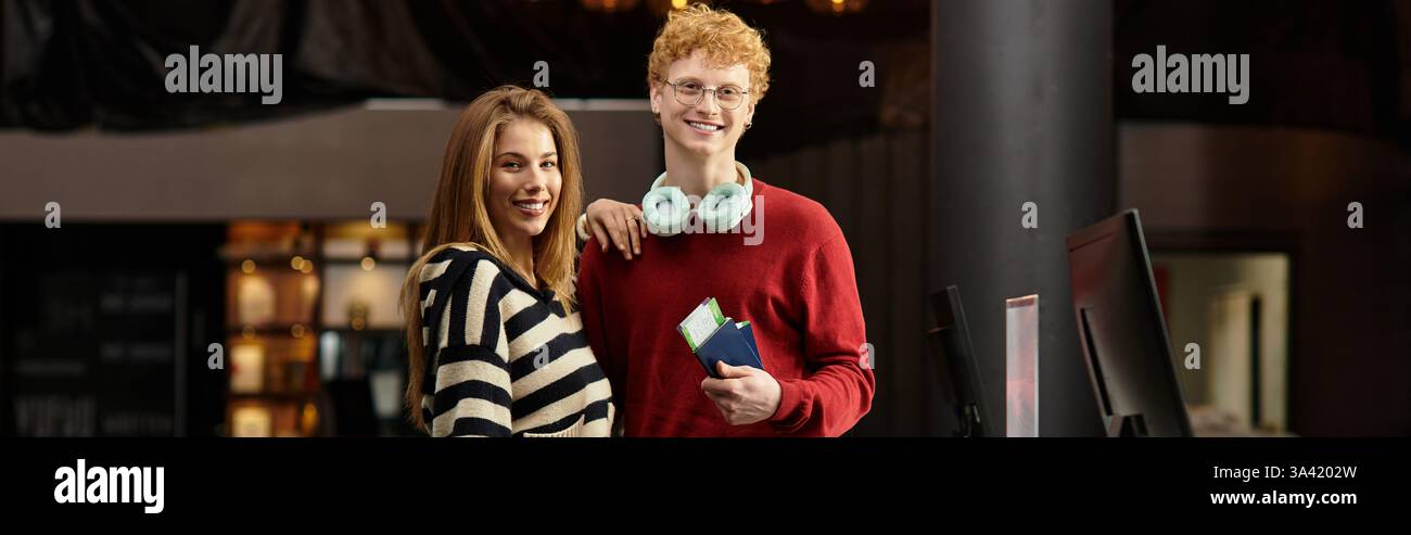 Ein junges Paar lächelt an der Hotelrezeption, bereit für ihre aufregende Reise der Liebe. Stockfoto