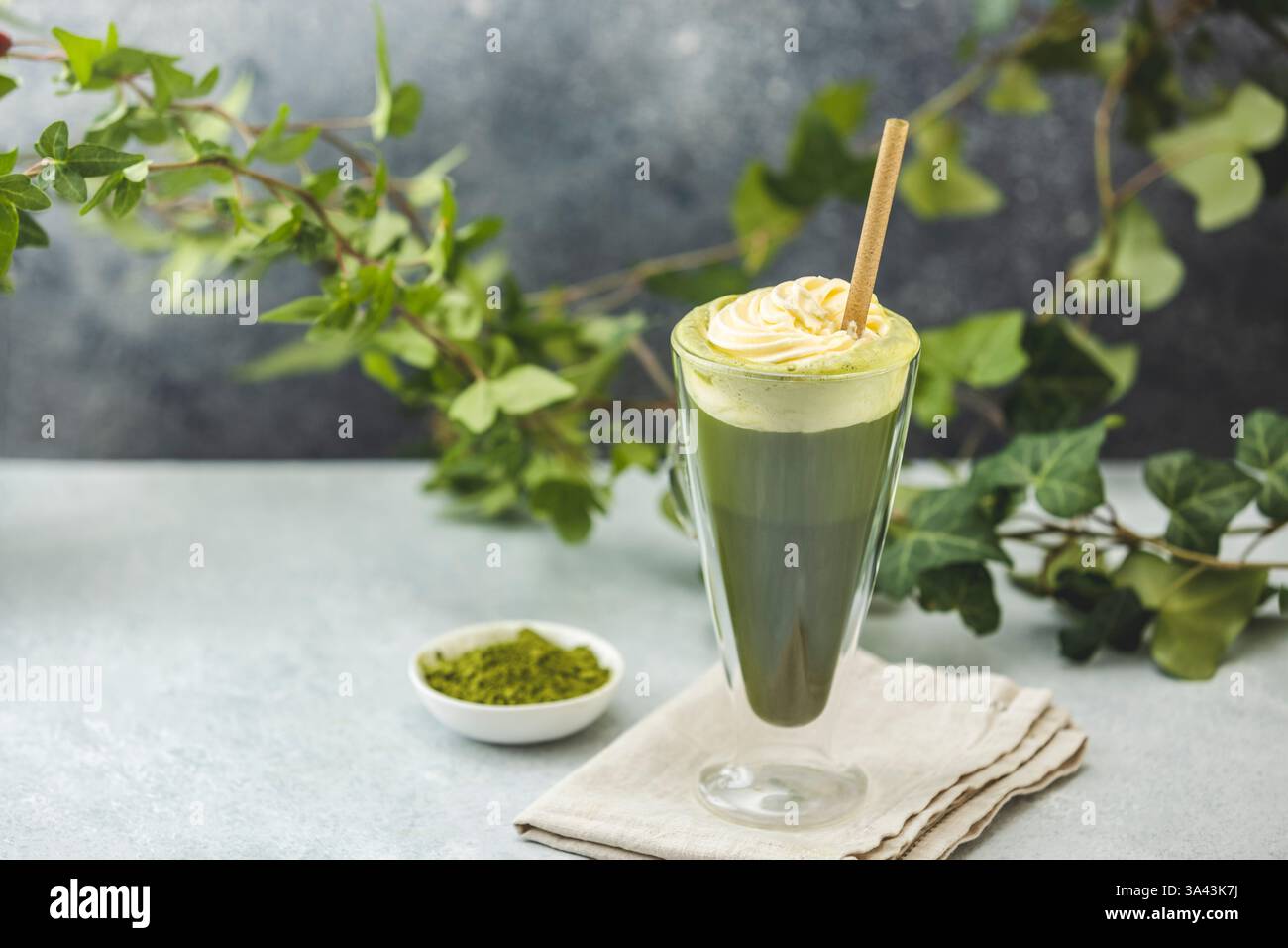 Zubereitung eines gefrorenen Matcha Latte, garniert mit Schlagsahne und garniert mit frischen Efeuzweigen, für ein erfrischendes Sommergetränk Stockfoto