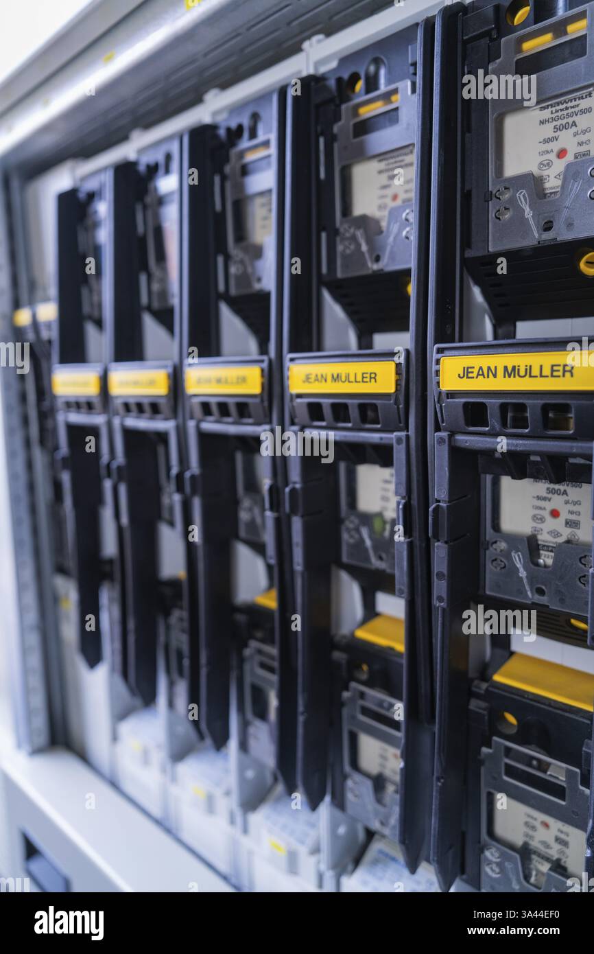 Reihe schwarzer Stromzähler eines bestimmten Herstellers, ordentlich in einer elektronischen Schalttafel angeordnet, Schaltschrankkonstruktion, PV-Systemkonstruktion Stockfoto