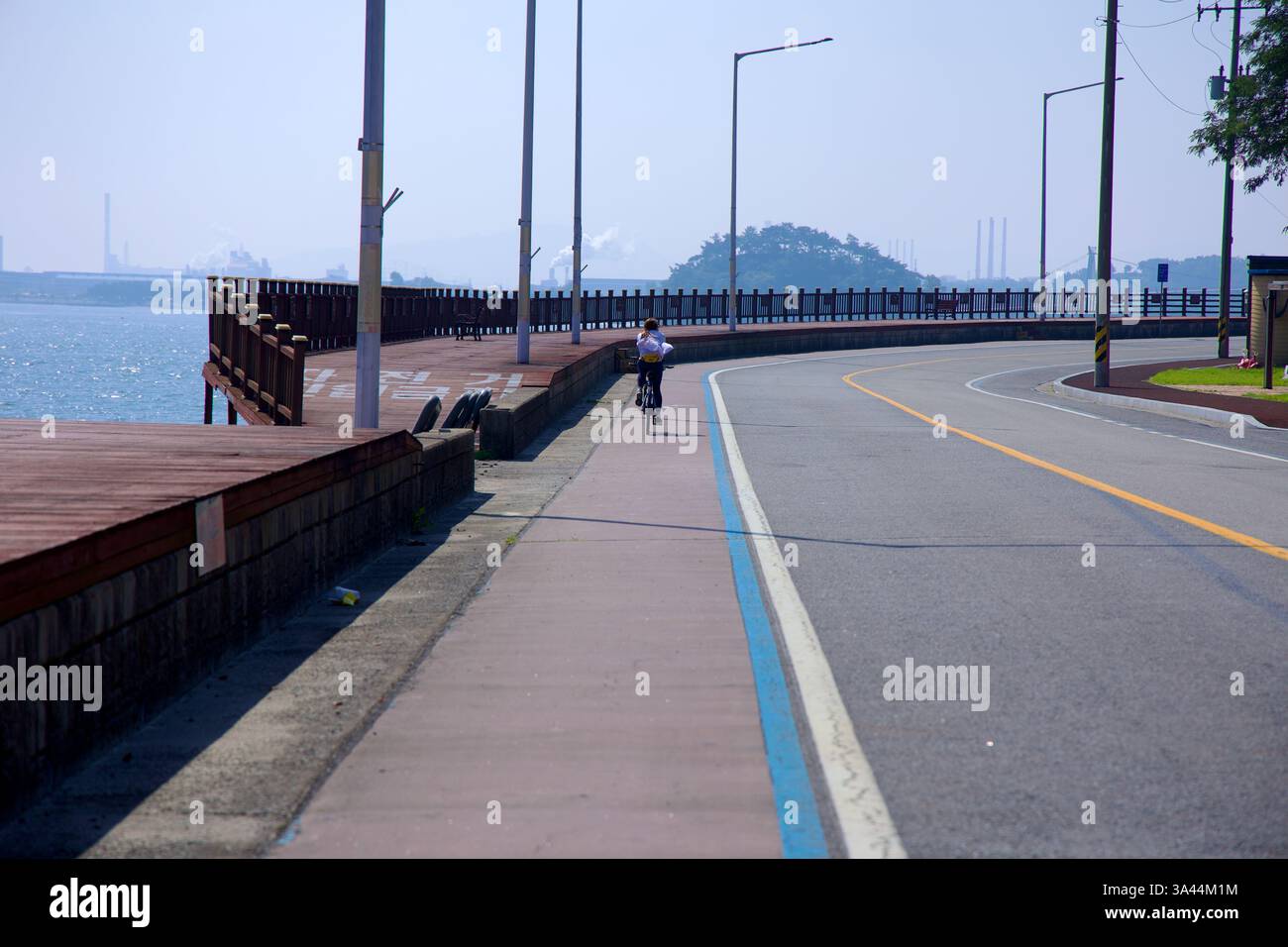 Gwangyang City, Südkorea - 3. Oktober 2021: Ein Radfahrer fährt auf einem ausgewiesenen Radweg entlang des Seomjin River, mit einem angrenzenden Holzsteg Stockfoto