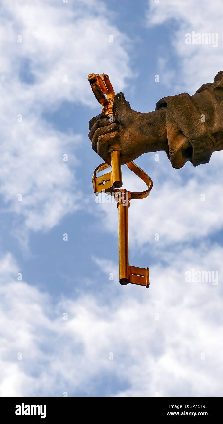 Hand hält einen goldenen Vintage-Schlüssel vor blauem Himmel, symbolische Freiheitsfotografie Stockfoto