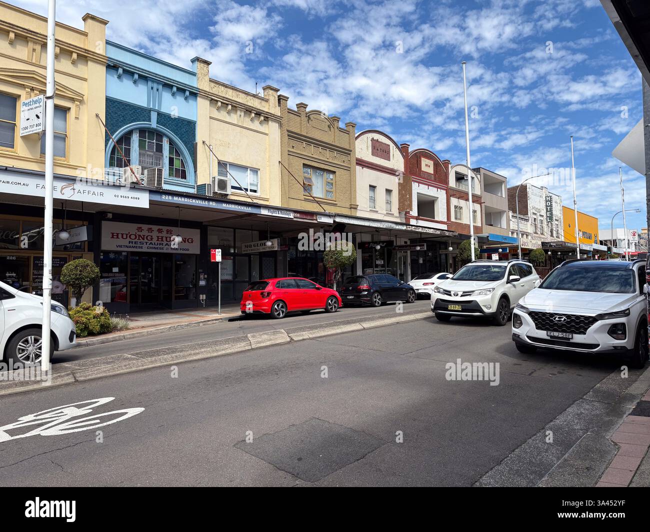 Straßenszene in Marrickville, NSW an einem sonnigen Tag mit Restaurants, Geschäften und Autos. Stockfoto