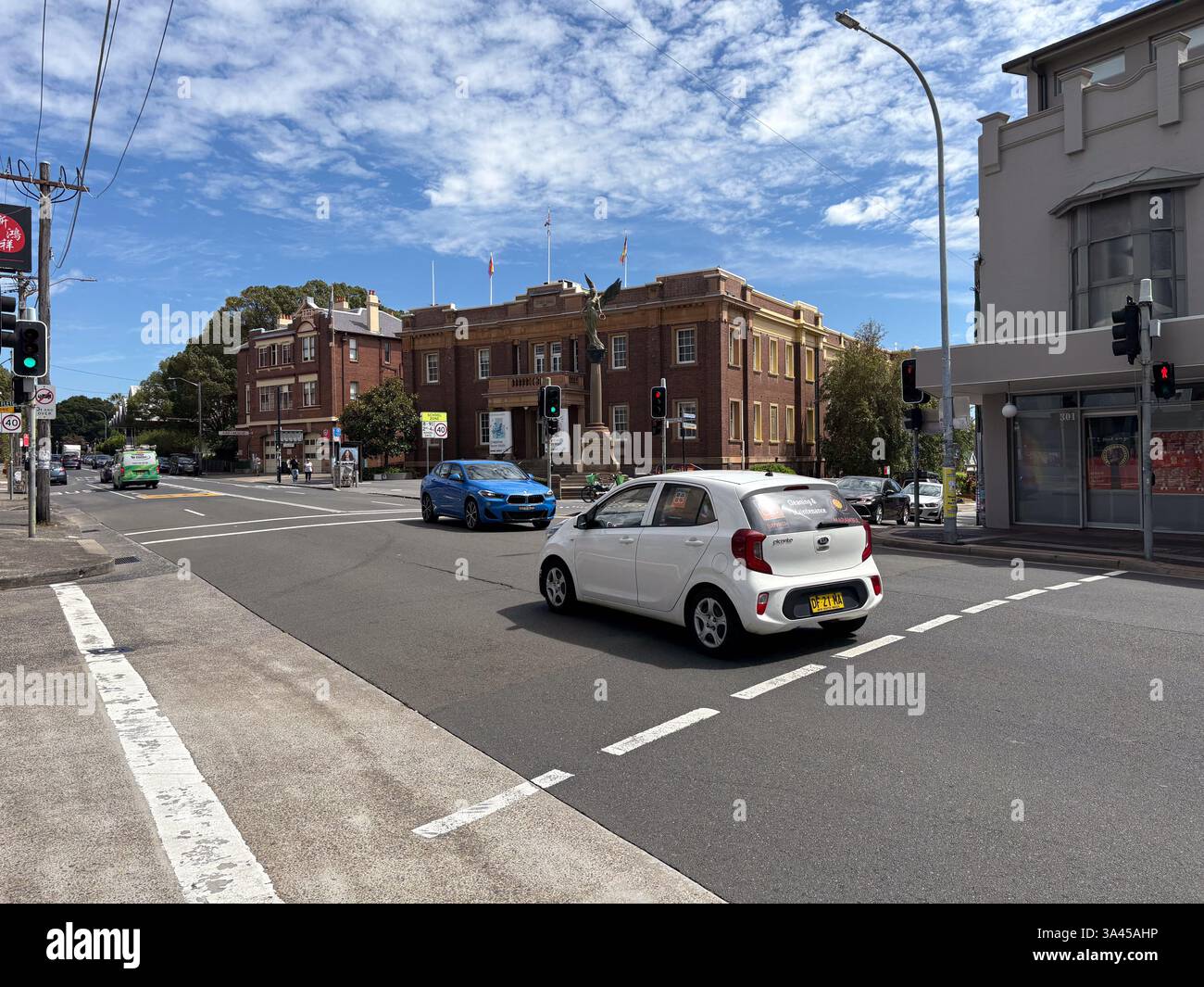 Auto und Verkehr bewegen sich entlang einer Straße in Marrickville, Australien, unter blauem Himmel. Stockfoto