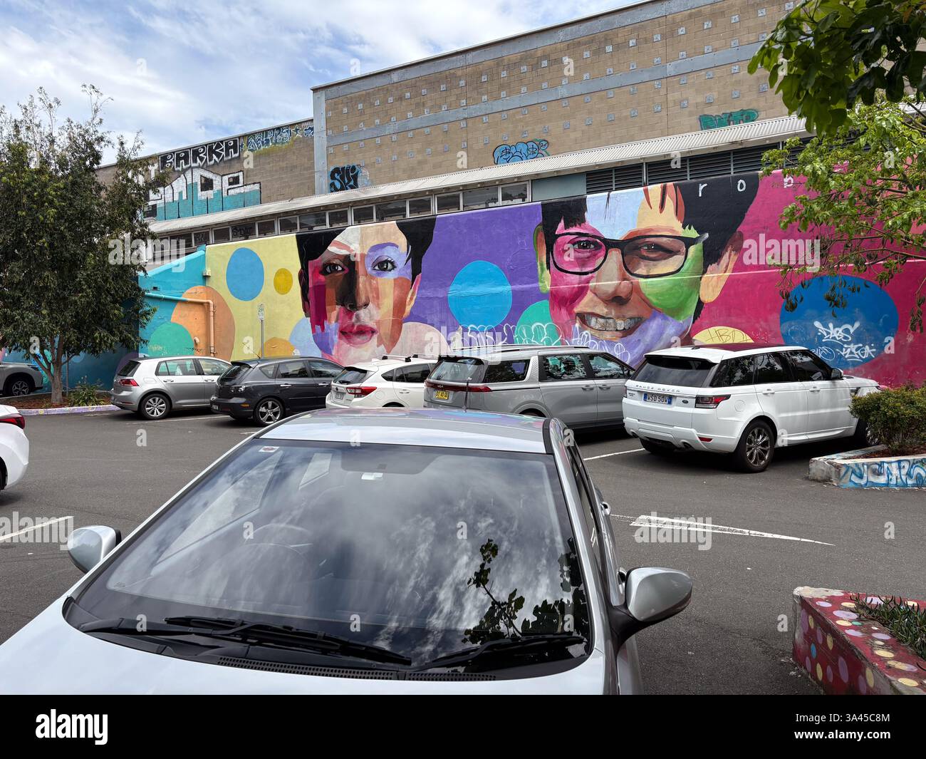 Ein Auto mit Porträt als Hintergrund mit Blick auf das Gebäude von oben auf einem Parkplatz mit anderen geparkten Autos. Stockfoto