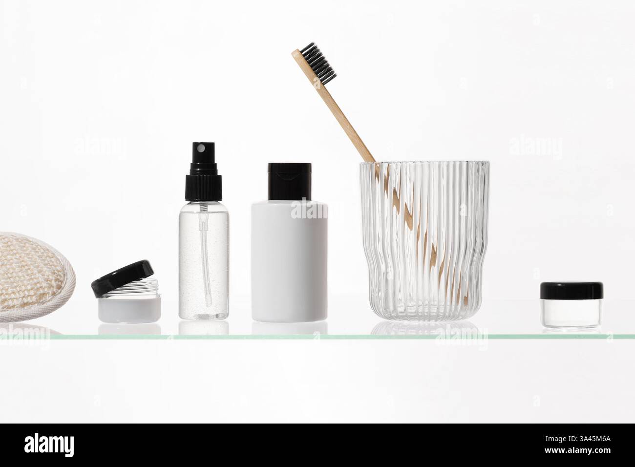 Verschiedene kosmetische Produkte auf einem Glasregal auf weißem Hintergrund. Mockup von Hautpflege- und Badeprodukten auf einem Glasregal. Spender und Röhrchen Stockfoto