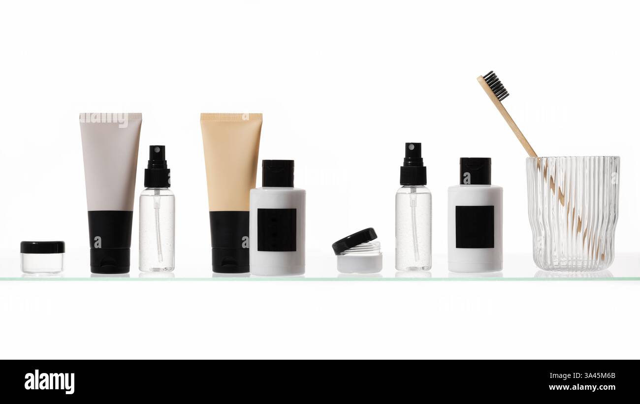 Verschiedene kosmetische Produkte auf einem Glasregal auf weißem Hintergrund. Mockup von Hautpflege- und Badeprodukten auf einem Glasregal. Spender und Röhrchen Stockfoto